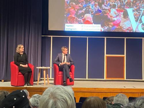 Catrin Jones and Tristram Hunt, sitting on orange chairs, on the stage in the Westminster Theatre